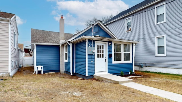 view of front of property featuring a front lawn and a shingled roof