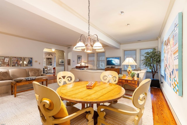 dining room featuring arched walkways, light wood-style flooring, crown molding, and an inviting chandelier