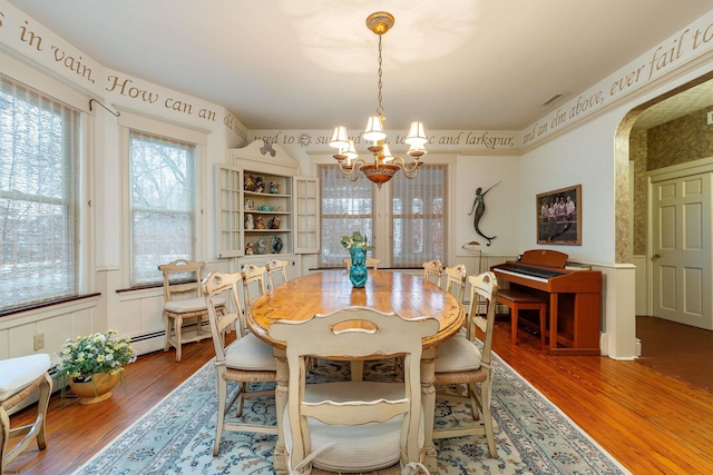 dining room featuring visible vents, a baseboard heating unit, an inviting chandelier, wood finished floors, and arched walkways