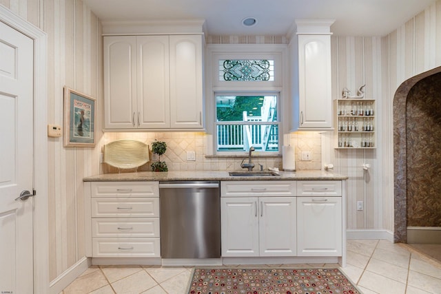 kitchen featuring dishwasher, light tile patterned floors, arched walkways, and a sink