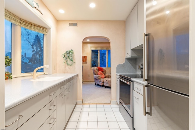 kitchen with visible vents, a sink, white cabinetry, arched walkways, and appliances with stainless steel finishes