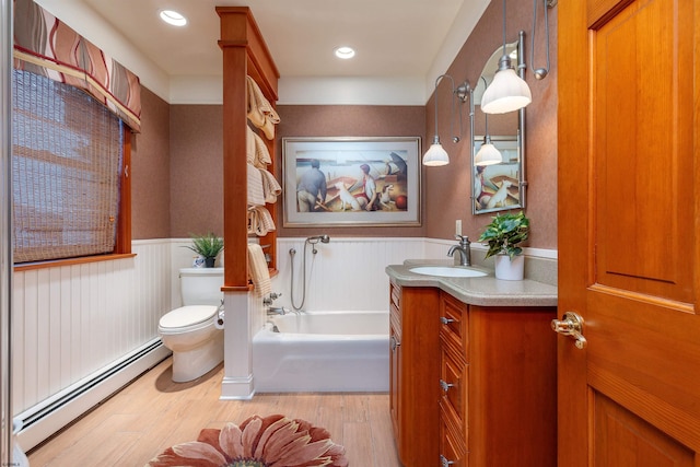 bathroom featuring a wainscoted wall, toilet, a garden tub, wood finished floors, and a baseboard radiator