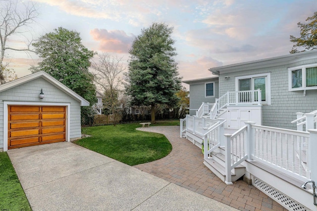 view of yard with an outbuilding, driveway, a detached garage, and fence