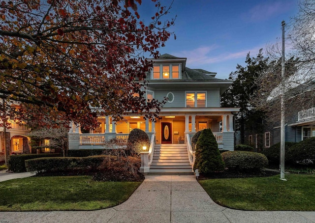 traditional style home with covered porch, stairs, and a front lawn