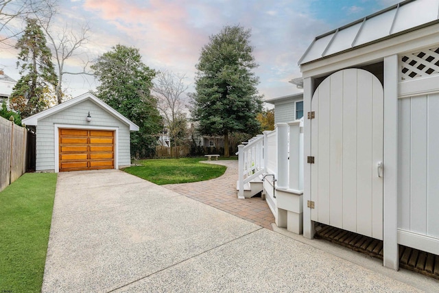 exterior space featuring a garage, an outdoor structure, driveway, and fence