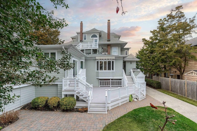 view of front of house featuring stairway, a balcony, fence, and driveway