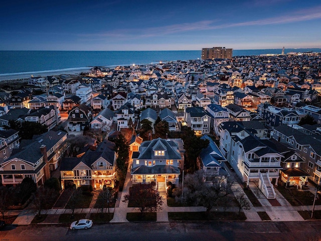 aerial view at dusk featuring a residential view and a water view