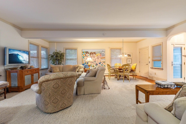 living room with arched walkways, a notable chandelier, carpet floors, and ornamental molding