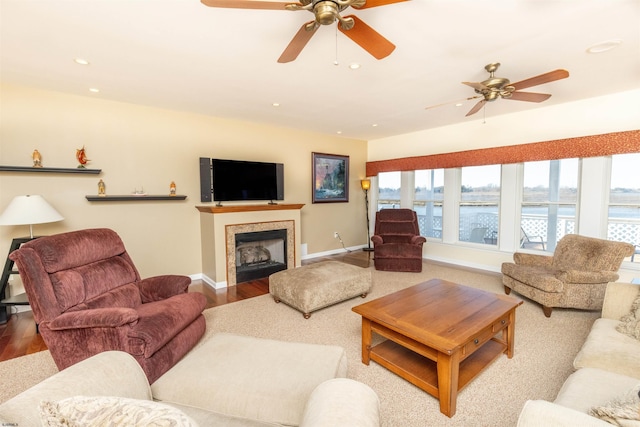 living area with a ceiling fan, wood finished floors, baseboards, recessed lighting, and a fireplace