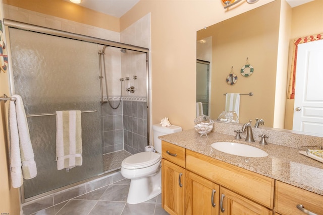 bathroom featuring tile patterned floors, vanity, toilet, and a shower stall