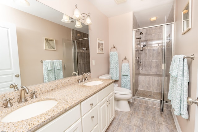 bathroom featuring a shower stall, toilet, double vanity, and a sink