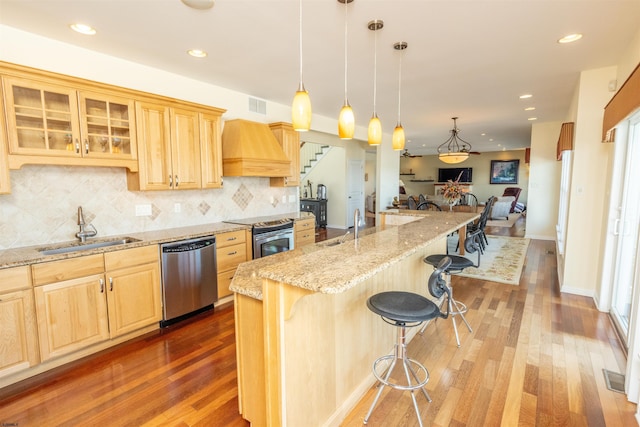 kitchen featuring visible vents, premium range hood, a kitchen breakfast bar, stainless steel appliances, and a sink