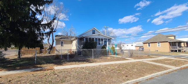 bungalow-style house featuring a fenced front yard and a sunroom