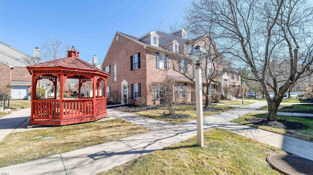 view of front of property featuring a gazebo, brick siding, and a front yard