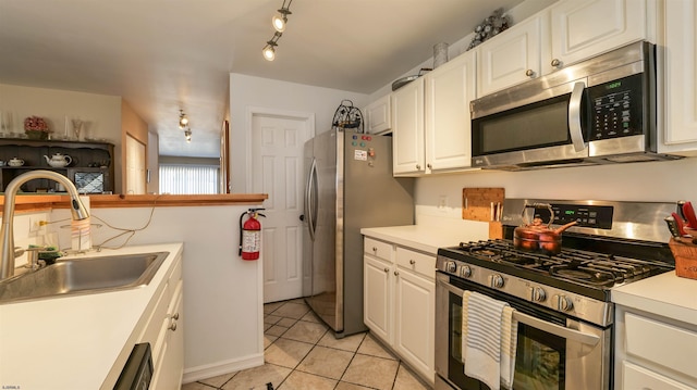 kitchen featuring a sink, appliances with stainless steel finishes, white cabinets, light countertops, and light tile patterned floors