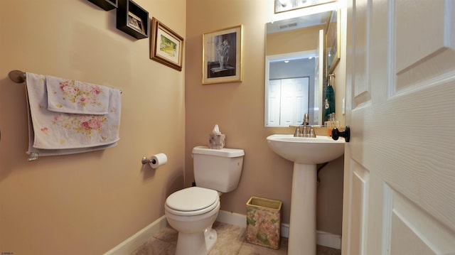 half bathroom with visible vents, toilet, a sink, tile patterned flooring, and baseboards