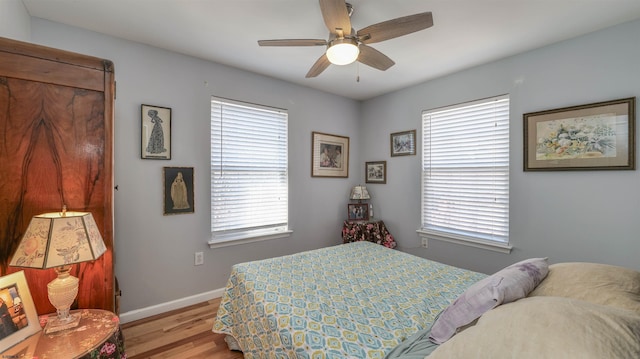 bedroom with light wood-type flooring, baseboards, and a ceiling fan