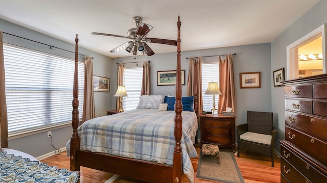 bedroom with baseboards, multiple windows, a ceiling fan, and light wood finished floors