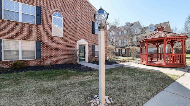 view of property exterior with a gazebo, a yard, and brick siding