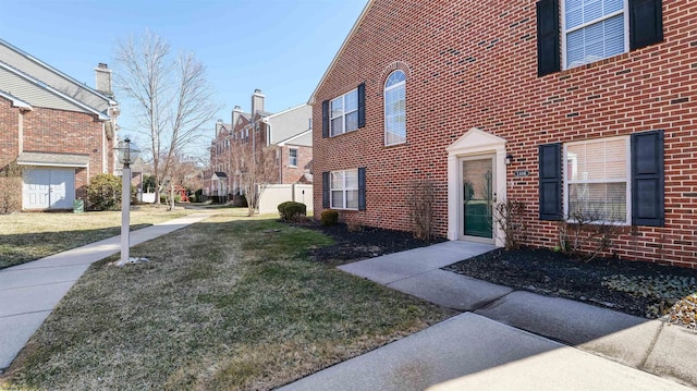 view of home's exterior featuring brick siding, a residential view, and a lawn