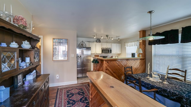 kitchen with track lighting, baseboards, stainless steel appliances, hanging light fixtures, and white cabinetry