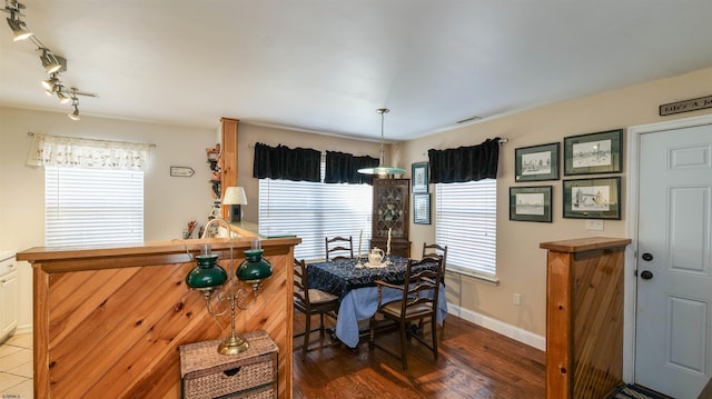 dining space with visible vents, rail lighting, wood finished floors, and baseboards