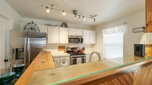 kitchen with white cabinets, stainless steel appliances, and wood counters