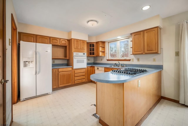 kitchen with a sink, light floors, a peninsula, white appliances, and open shelves