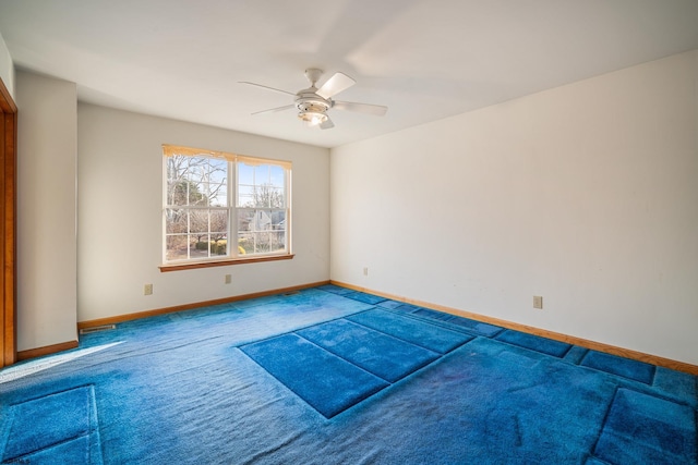 carpeted empty room with a ceiling fan and baseboards