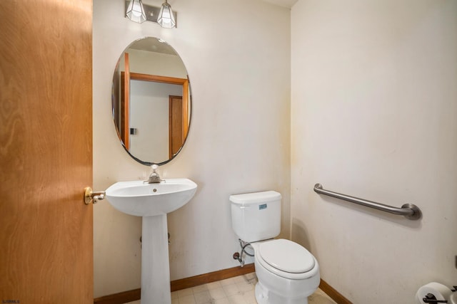 half bath with tile patterned floors, baseboards, toilet, and a sink