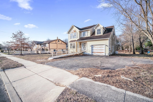 view of front of house with aphalt driveway, a garage, and fence