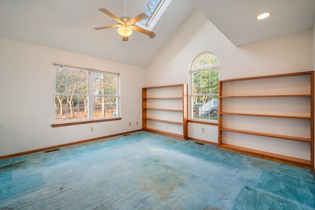 carpeted spare room with visible vents, baseboards, lofted ceiling with skylight, recessed lighting, and a ceiling fan