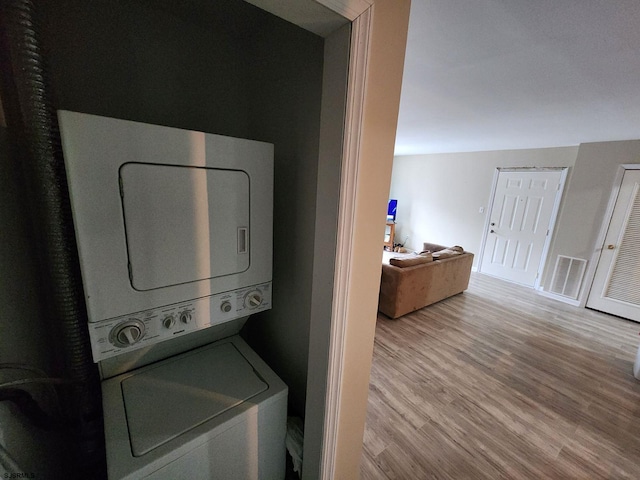 laundry room with stacked washer / drying machine, visible vents, and wood finished floors