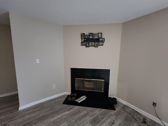 interior details with baseboards, a fireplace with flush hearth, and wood finished floors