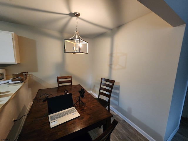 dining space featuring a chandelier, dark wood finished floors, and baseboards