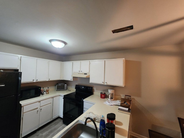 kitchen featuring under cabinet range hood, white cabinetry, black appliances, and light countertops