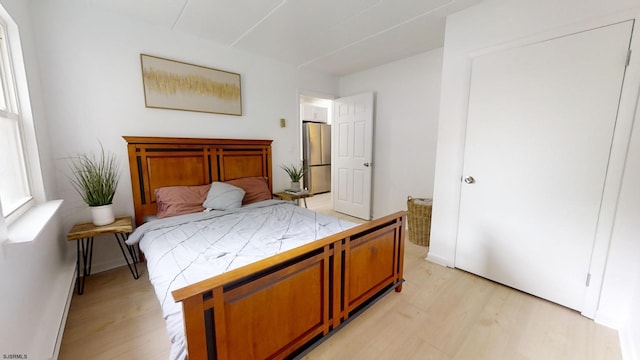 bedroom featuring light wood-style flooring and freestanding refrigerator