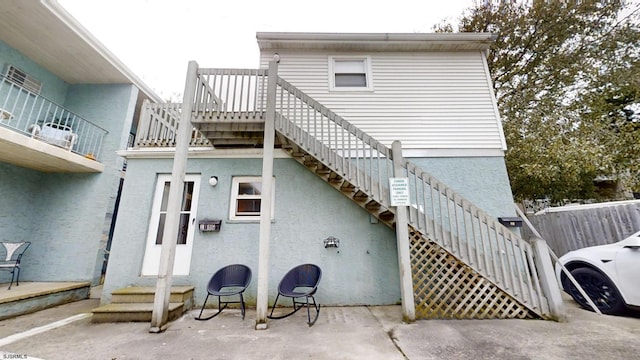 back of property featuring stucco siding and stairs