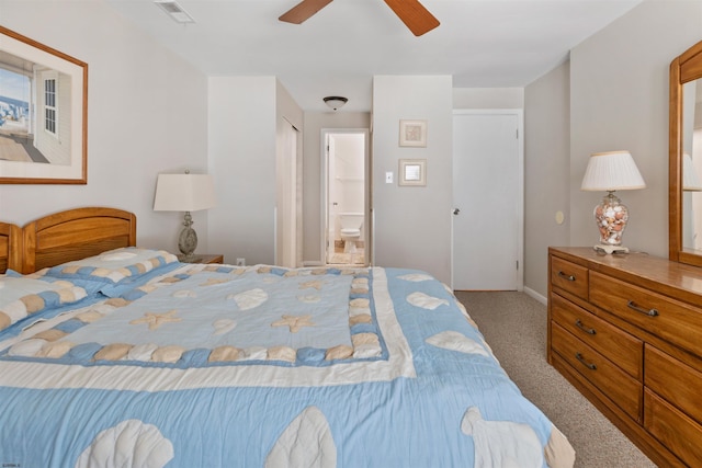 carpeted bedroom with visible vents, ensuite bath, and a ceiling fan