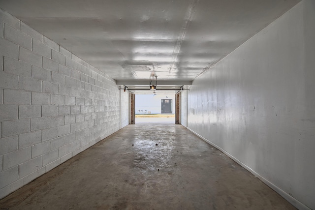 garage with electric panel, a garage door opener, and concrete block wall