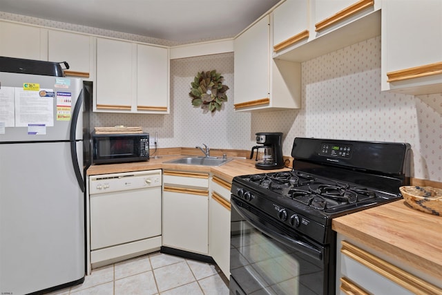 kitchen with wallpapered walls, black appliances, light tile patterned floors, and a sink