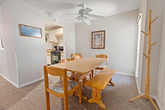 dining area featuring light colored carpet, baseboards, and a ceiling fan