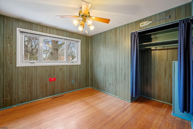 unfurnished bedroom featuring visible vents, a ceiling fan, wood finished floors, a closet, and baseboards