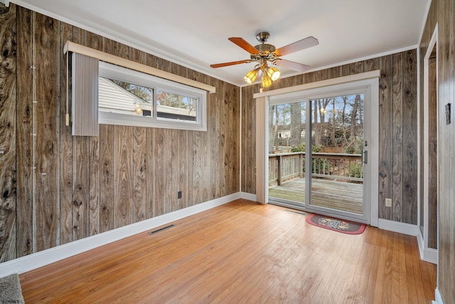 unfurnished room with visible vents, wood walls, and hardwood / wood-style flooring