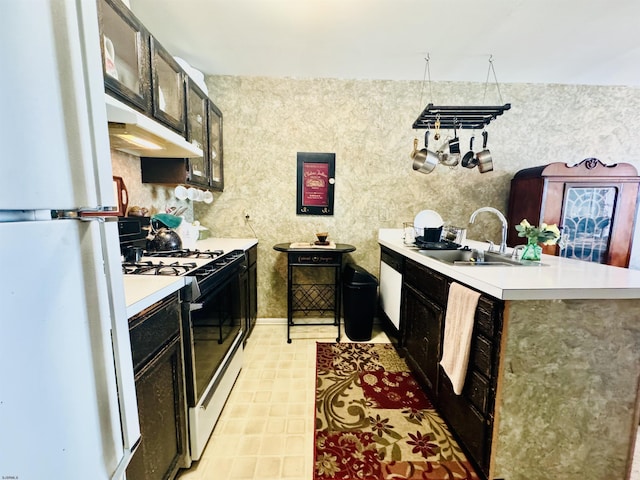 kitchen featuring white appliances, a peninsula, light countertops, and a sink