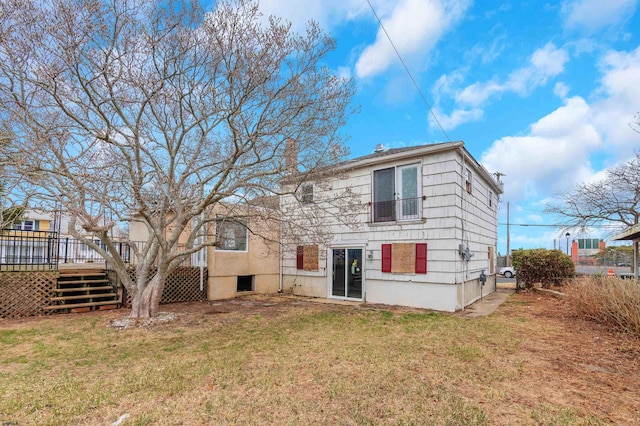 back of property with a wooden deck, a lawn, and stairs