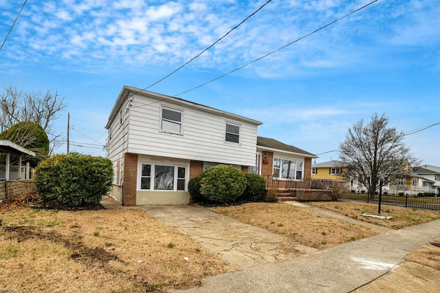 split level home with brick siding, driveway, and fence