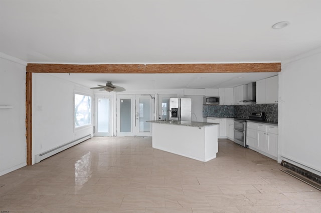 kitchen featuring stainless steel appliances, white cabinets, a baseboard heating unit, wall chimney exhaust hood, and backsplash