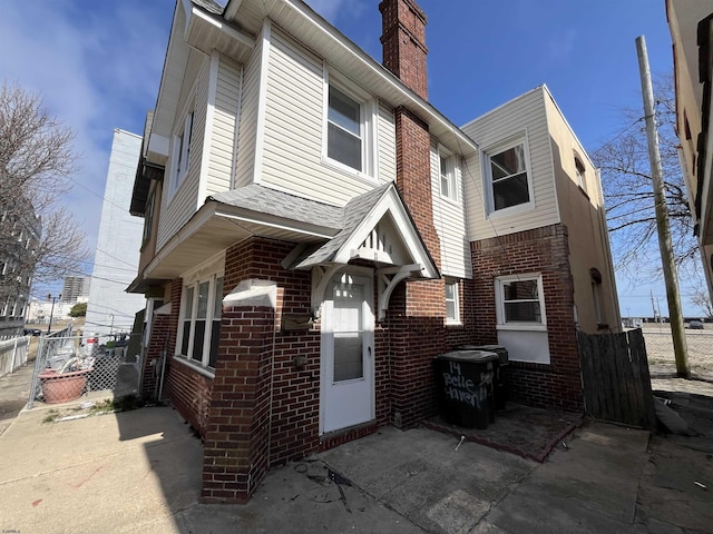 exterior space with brick siding, a chimney, and fence