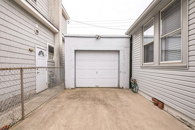 garage featuring concrete driveway and fence